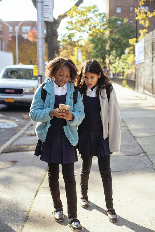 内容多样的女学生在大街上行走和使用智能手机 · 免费素材图片