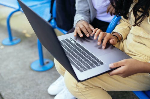 作物在街道长凳上的笔记本电脑上上网的多民族小学生上网 · 免费素材图片