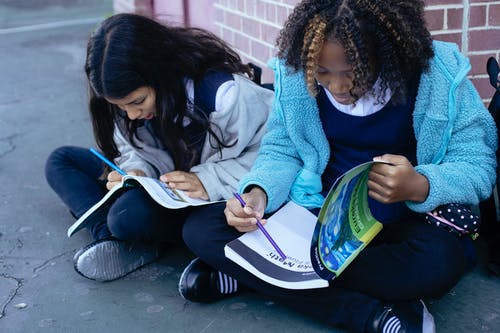 用铅笔在教科书中锻炼的多种族儿童 · 免费素材图片