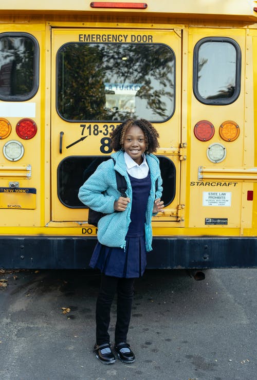 快乐的民族小学生在城市道路上的公共汽车附近 · 免费素材图片