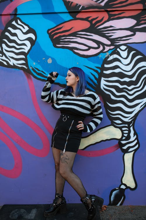 黑色和白色的条纹的长袖衬衫和黑色的短裤，站在墙旁边的女人 · 免费素材图片