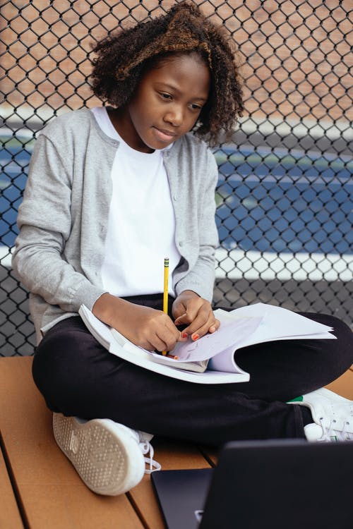 集中在长凳上的黑人女孩写作业 · 免费素材图片