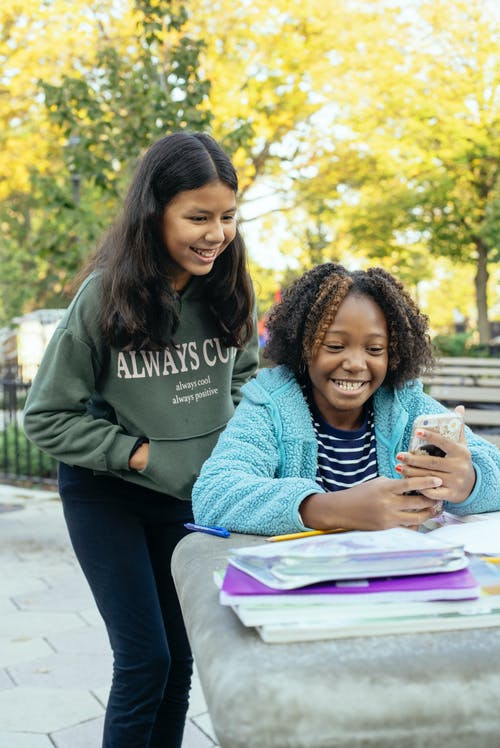 多种族的小女孩在一起浏览智能手机 · 免费素材图片