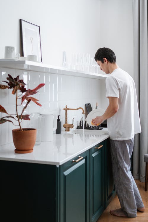 在厨房水槽上洗碗的人 · 免费素材图片