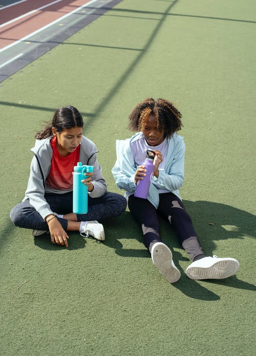 在运动场上的塑料瓶的多种族女孩 · 免费素材图片