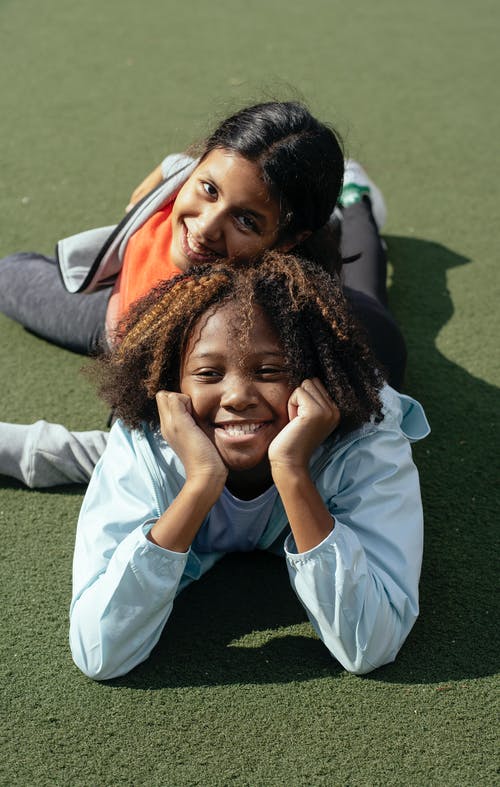 在运动场上放松的快乐多民族女学生 · 免费素材图片