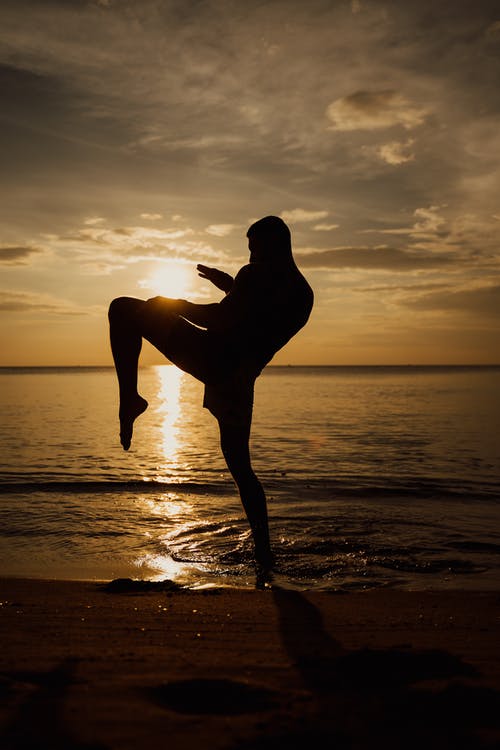 女人在日落时站在海滩上的剪影 · 免费素材图片