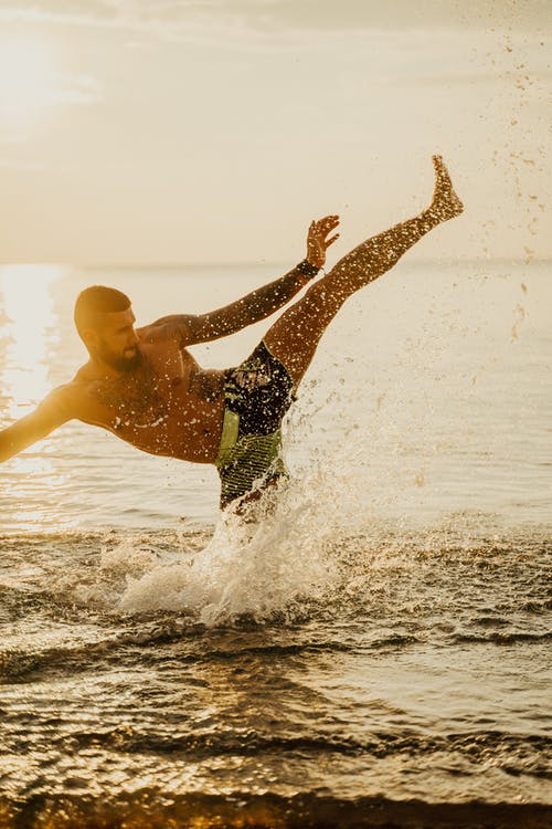 黑色短裤在水面上跳跃的人 · 免费素材图片