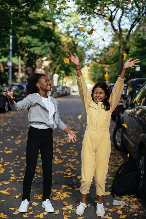秋天的落叶在大街上玩的快乐多样有趣的女孩 · 免费素材图片