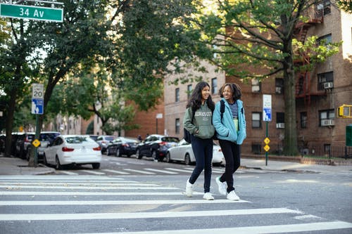 性格开朗的女学生在城市过马路 · 免费素材图片