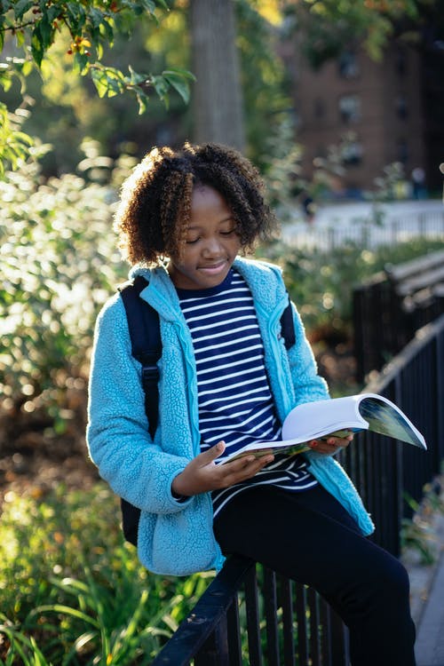 黑人小姑娘在公园里读书教科书 · 免费素材图片