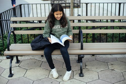 性格开朗的西班牙裔女孩，教科书在长凳上 · 免费素材图片