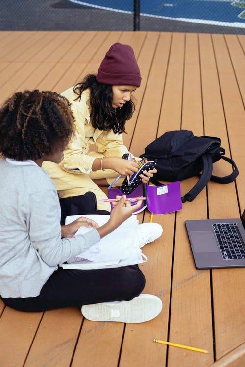 在木制平台上学习时无法识别的多民族小学生共享笔记本电脑 · 免费素材图片
