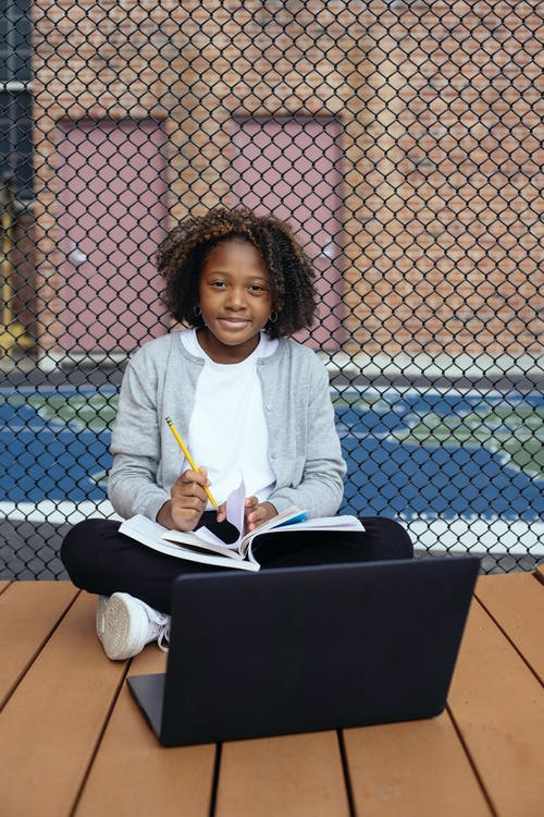 有笔记本和膝上型计算机的微笑的种族女孩 · 免费素材图片