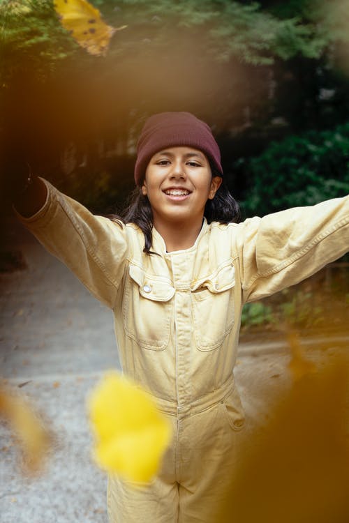 微笑的西班牙裔女孩，在公园里举起双手 · 免费素材图片