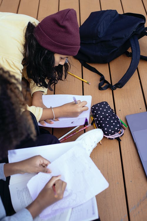 作物多民族的女学生一起学习时在抄写本上记笔记 · 免费素材图片