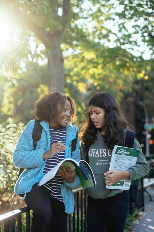 性格开朗的多样化女学生与工作簿在大街上聊天 · 免费素材图片