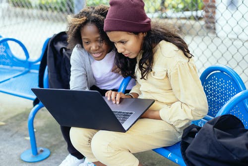作物多族裔学童在城市的长椅上看笔记本电脑 · 免费素材图片