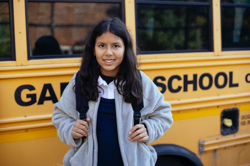 校车附近的快乐西班牙裔女孩 · 免费素材图片