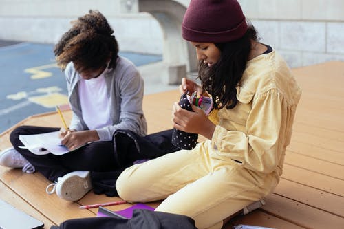 用铅笔盒在街上读书的多民族小学生 · 免费素材图片