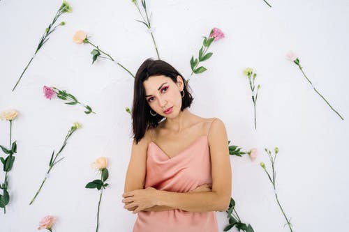 站在白色的花旁边的棕色背心的女人 · 免费素材图片