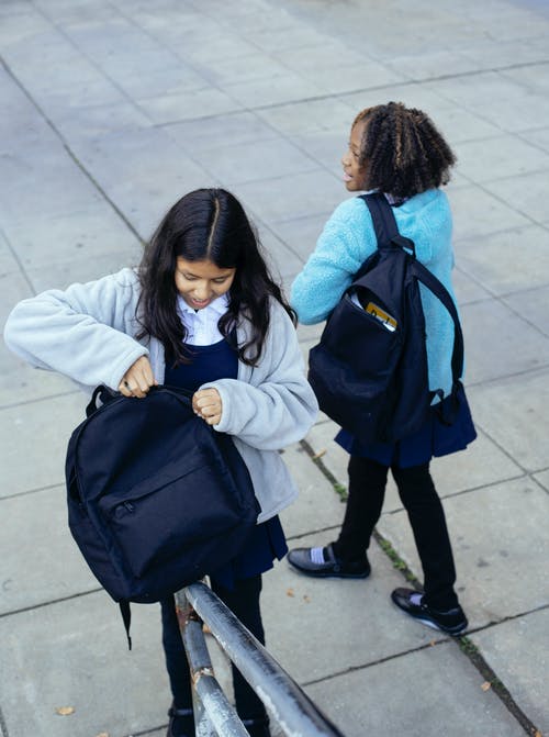 不同的女学生背着背包站在学校大楼外 · 免费素材图片