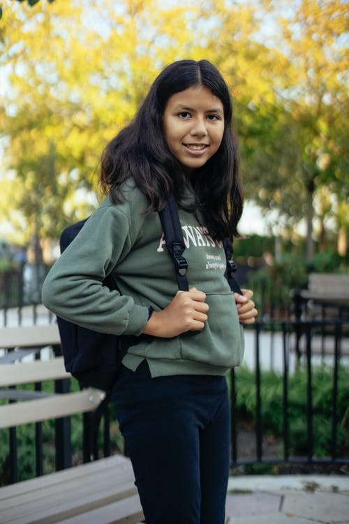 站立在公园的微笑的西班牙女小学生 · 免费素材图片