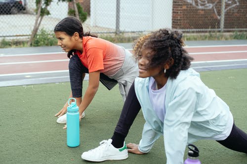 多种族的嬉戏女孩在跑道上锻炼前的热身 · 免费素材图片