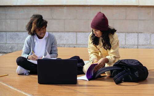 不同的女学生在街上笔记本电脑附近学习时聊天 · 免费素材图片