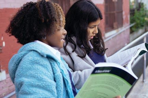 可爱的重点多样的女孩读教科书 · 免费素材图片