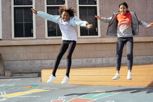 激动的多种族同学跳下学校附近的木制场景 · 免费素材图片