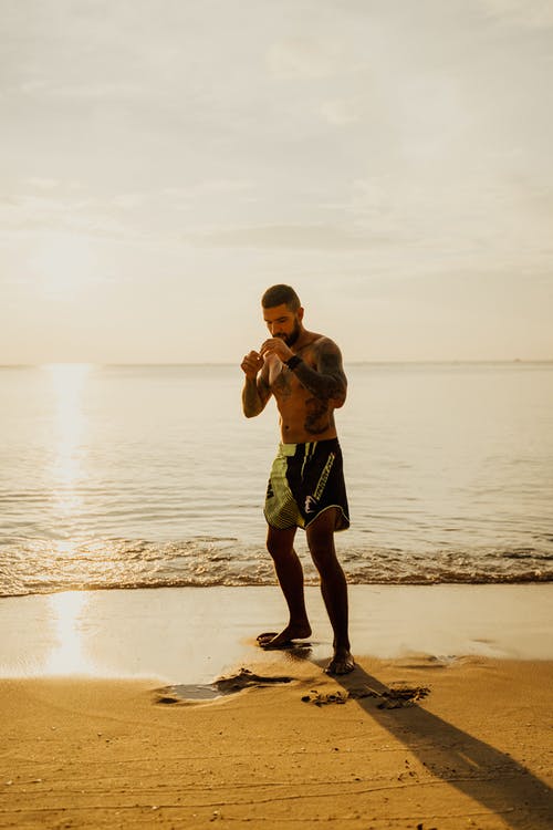 黑色短裤站在日落海滩上的男孩 · 免费素材图片
