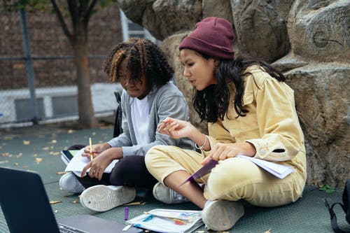多民族的女学生在学习和在人行道上聊天时看笔记本电脑 · 免费素材图片