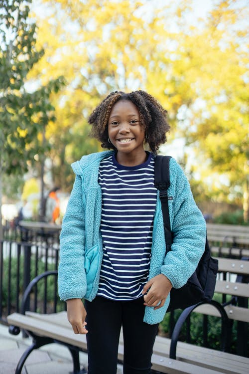 站立在公园的愉快的黑人女小学生 · 免费素材图片