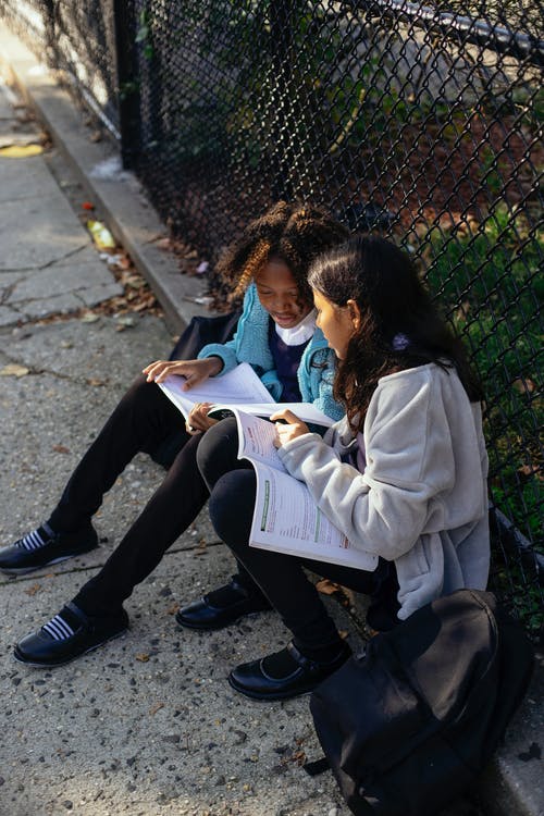 勤奋的多民族女学生在秋天公园阅读教科书 · 免费素材图片