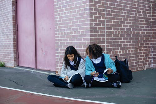 多民族的女孩谈论学校和写在教科书中 · 免费素材图片