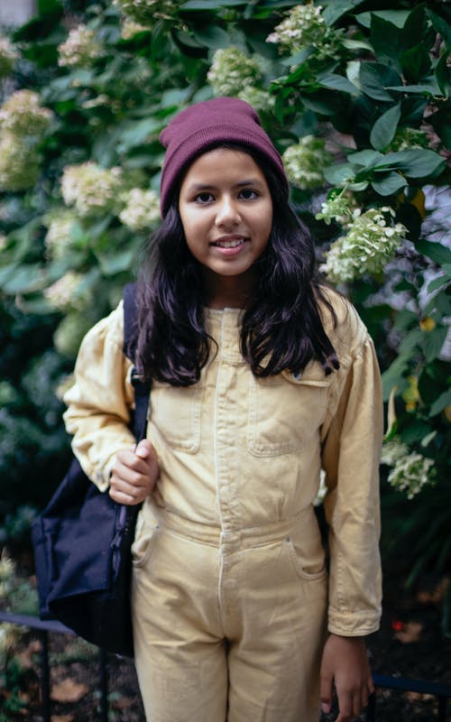 微笑在盛开的布什附近的可爱的西班牙裔女孩 · 免费素材图片