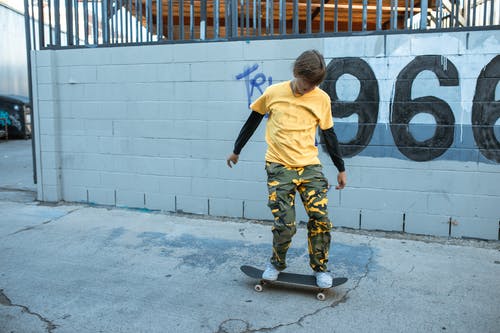 黄色衬衫和绿色的裤子，站在灰色的水泥地板上的男孩 · 免费素材图片