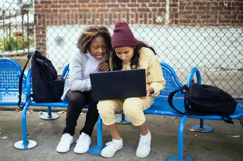 惊讶的多民族小学生在城市的长椅上看笔记本电脑 · 免费素材图片