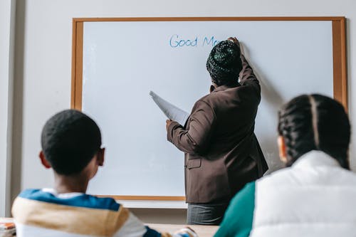 在白板上为不同学生写作的黑人老师 · 免费素材图片