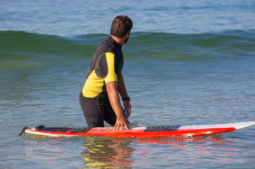 匿名男冲浪者站在海水中，等待波 · 免费素材图片