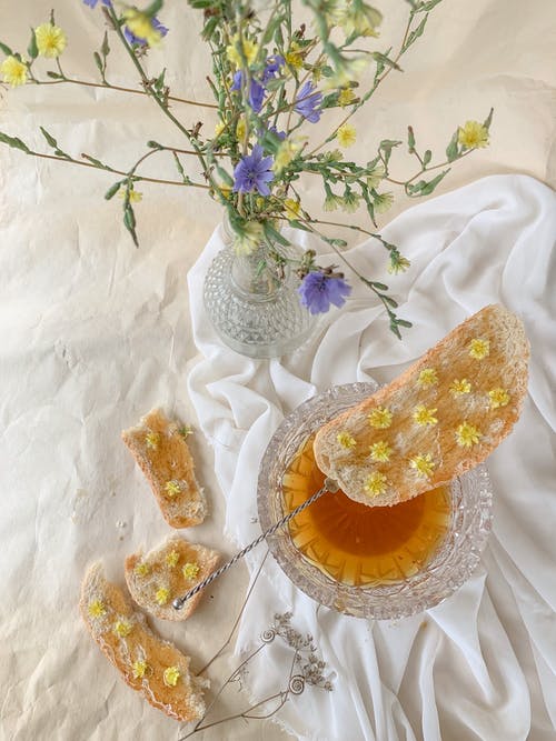 面包用蜂蜜在花瓶附近的花 · 免费素材图片