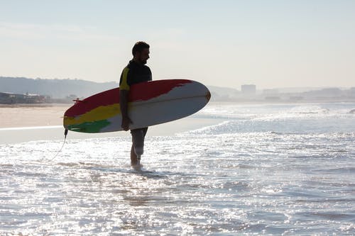 男性截肢者冲浪者与冲浪板站在海滩上的剪影 · 免费素材图片