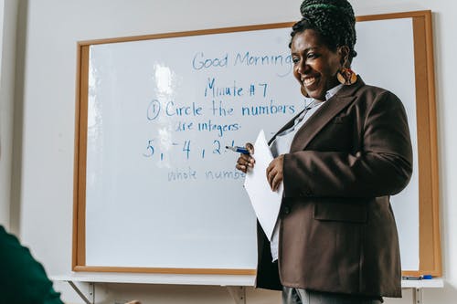 在教室里裁剪站立在白板附近的快乐的黑人女老师 · 免费素材图片