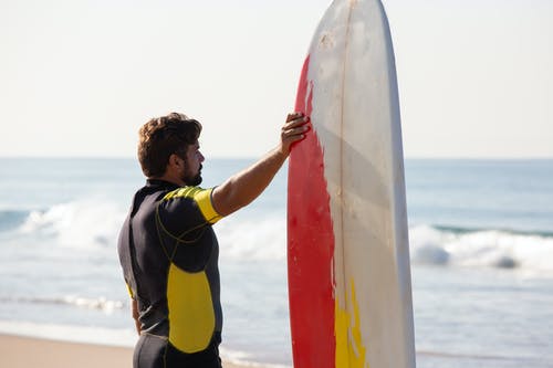 适合男性冲浪者站在风景如画的海滨，靠近冲浪板 · 免费素材图片