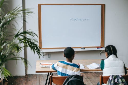 坐在教室的桌子上不露面的多样同学 · 免费素材图片