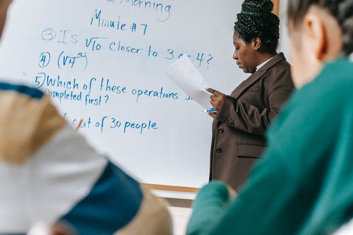 在白板上作物集中黑人女老师的写作任务 · 免费素材图片