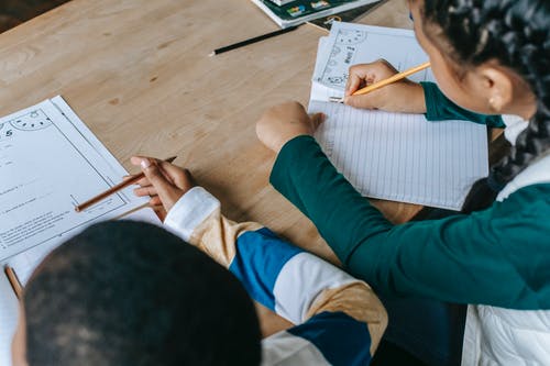 裁剪不露面的族裔学生在笔记本上做笔记 · 免费素材图片