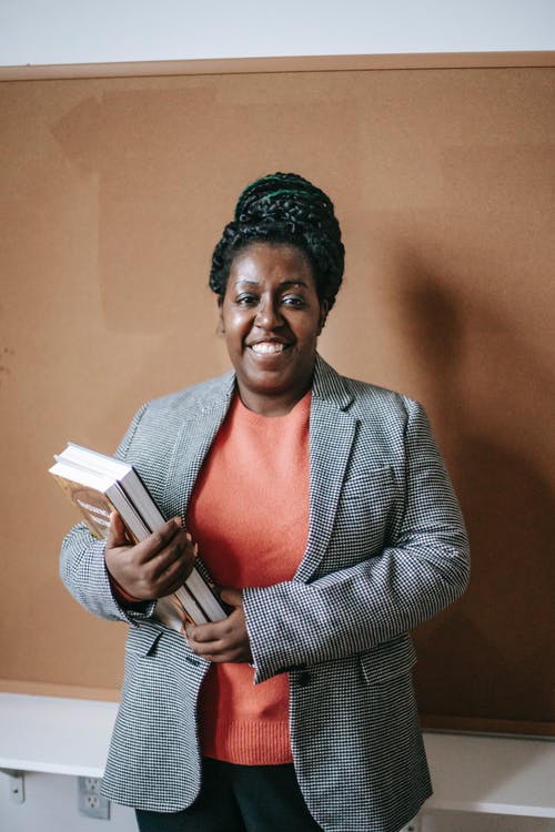 微笑与教科书的黑人女老师 · 免费素材图片