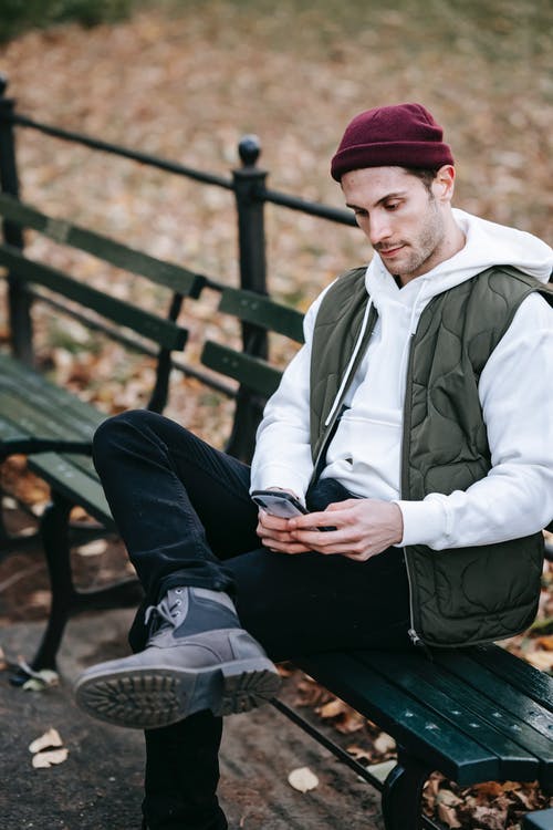 白色和蓝色的拉链外套，坐在棕色的木凳上的男人 · 免费素材图片